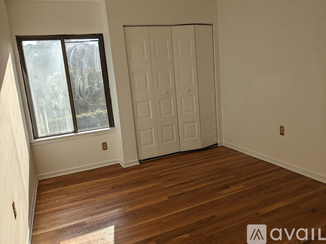 A room with a white door and a window with a view of trees.