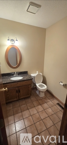 A bathroom with a toilet, sink, and mirror.
