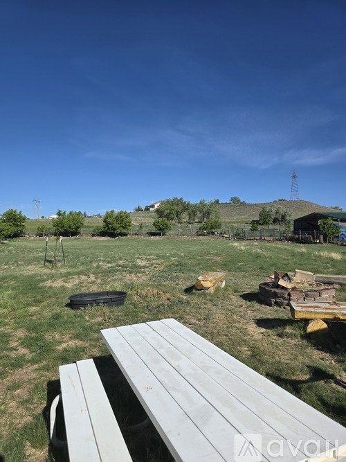 A picnic table is in the foreground of a grassy field.