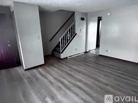 A spacious room with a staircase and wooden flooring.