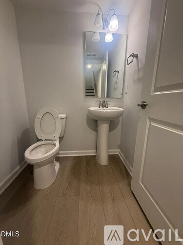A white toilet with a sink and mirror in a small bathroom.