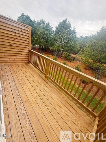 A wooden deck with a railing and trees in the background.