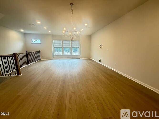 A spacious room with wooden flooring and a chandelier.