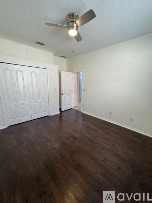 A room with a ceiling fan and wood flooring.
