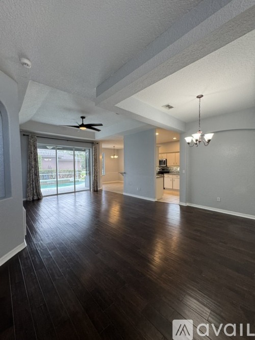 A spacious room with wood flooring and a ceiling fan.