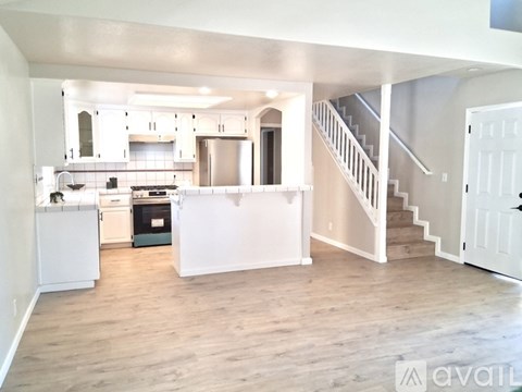 A kitchen with white cabinets and a stainless steel refrigerator.