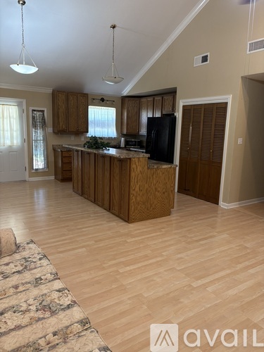 A kitchen with wooden cabinets and a black fridge.
