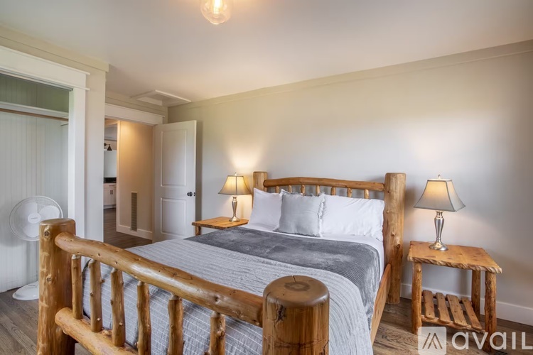 A bedroom with a large bed and two lamps.
