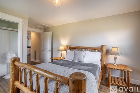A bedroom with a large bed and two lamps.