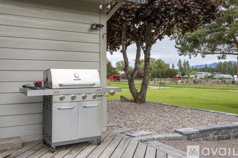 A BBQ grill is on a wooden deck outside a house.