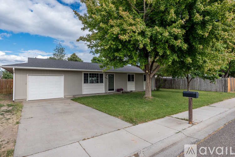 A house with a garage and a tree in front.