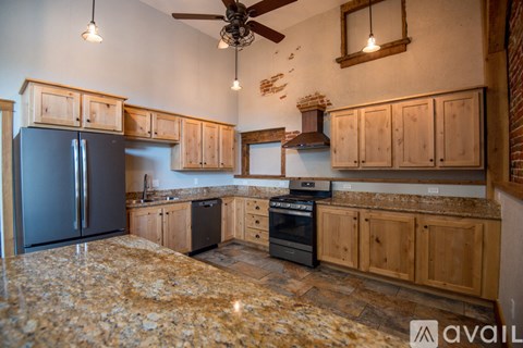 A kitchen with wooden cabinets and a black refrigerator.