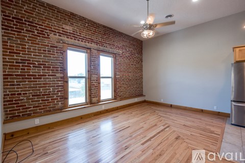 A room with a brick wall and wooden flooring is available for rent.