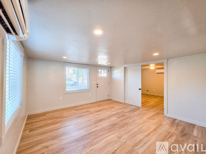 A spacious room with wooden flooring and white walls.