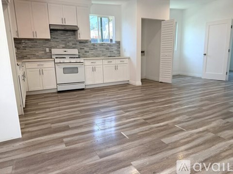 A kitchen with white cabinets and a stone backsplash.