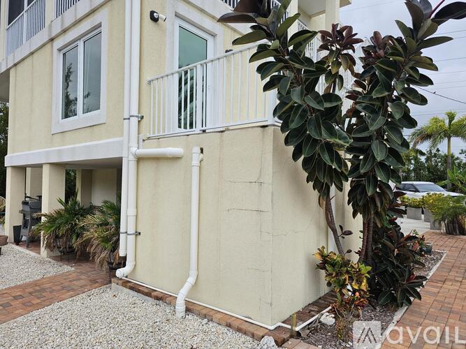 A white building with a balcony and a tree in front.