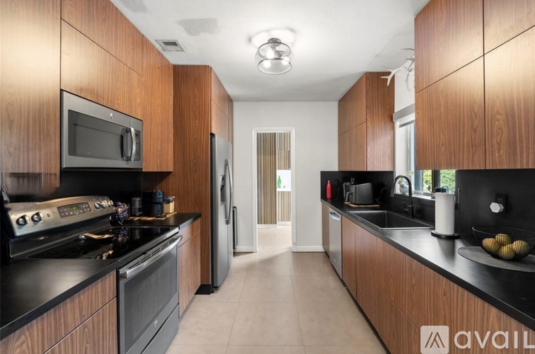 A kitchen with wooden cabinets and black countertops.