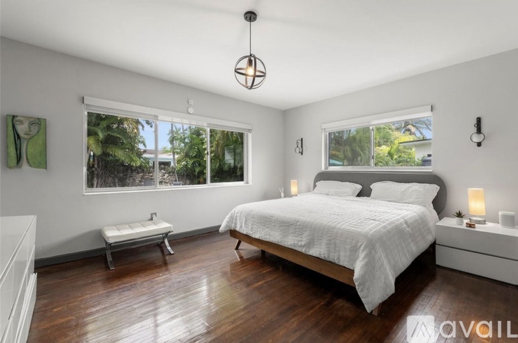 A bedroom with a large bed, a bench, and a window with a view of trees.