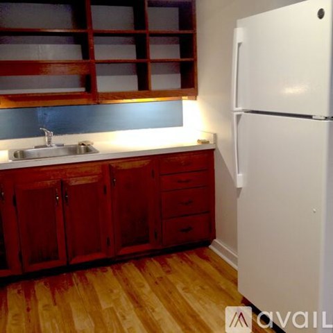 A kitchen with red cabinets and a white refrigerator.