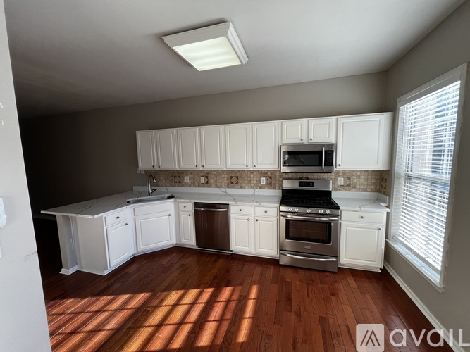 A kitchen with white cabinets and a stainless steel stove top oven.