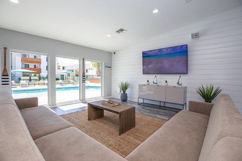 A living room with a large couch and a flat screen TV mounted on the wall.