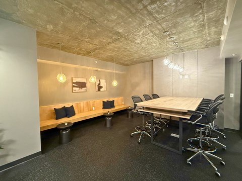 A conference room with a long table, chairs, and a bench with cushions.