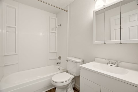A white bathroom with a toilet, sink, and bathtub.