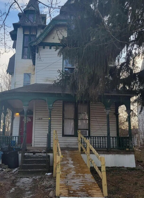 A white house with a red door and a porch.