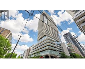 A tall building with many windows stands in front of other buildings.