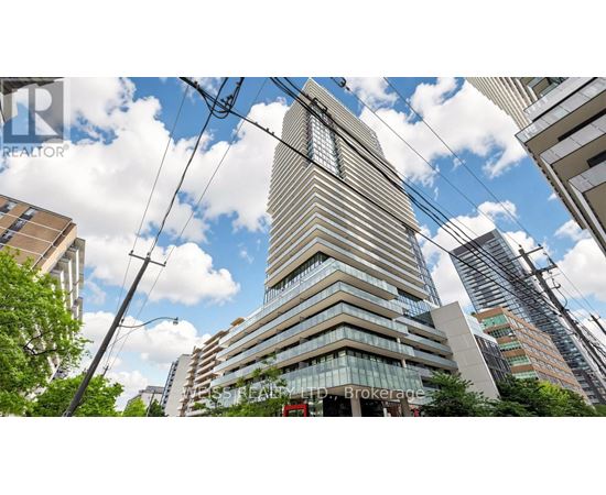 A tall building with many windows stands in front of other buildings.