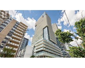 A tall building with a glass facade stands in the middle of a cityscape.