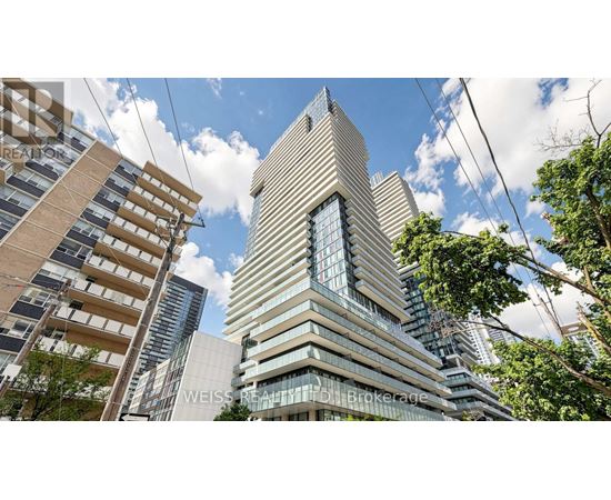 A tall building with a glass facade stands in the middle of a cityscape.