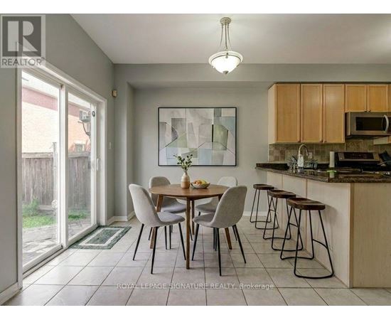 A dining room with a table set for two and a kitchen area with a microwave and oven.