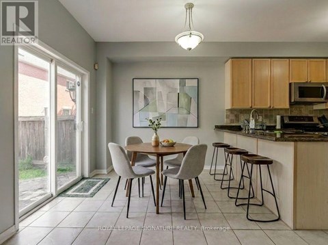 A dining room with a table set for two and a kitchen area with a microwave and oven.