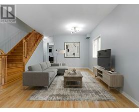 A living room with a grey couch, a wooden coffee table, and a staircase.