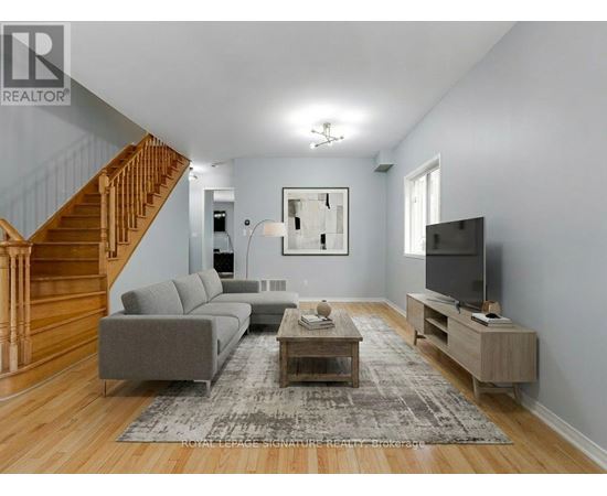 A living room with a grey couch, a wooden coffee table, and a staircase.
