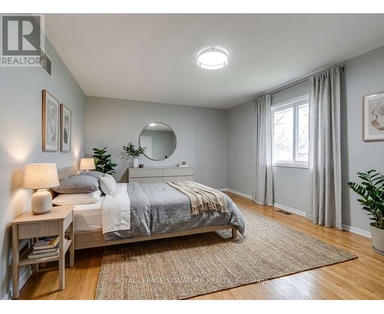 A bedroom with a bed, nightstand, and a mirror on the wall.