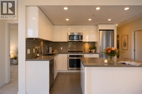 A modern kitchen with white cabinets and stainless steel appliances.
