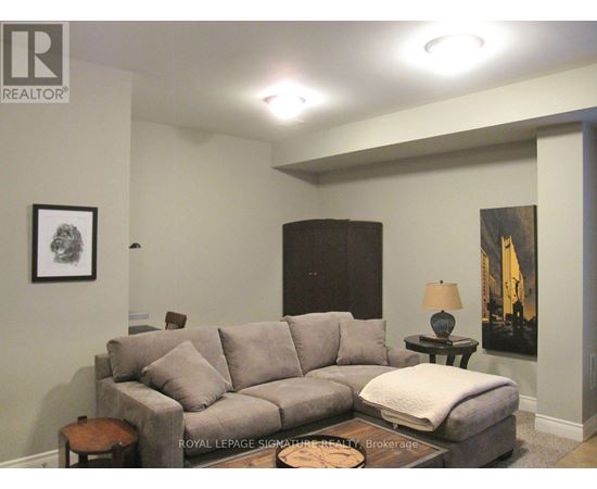 A living room with a grey couch and a small table with a lamp on it.