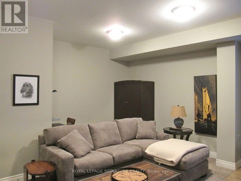 A living room with a grey couch and a small table with a lamp on it.