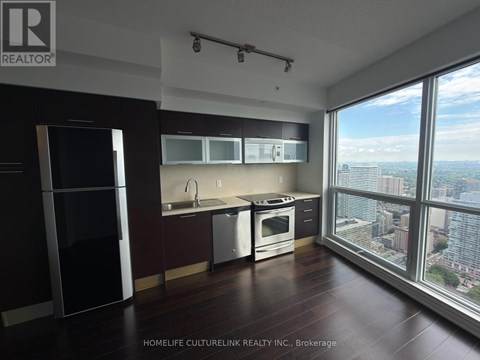A modern kitchen with dark wood floors and stainless steel appliances.