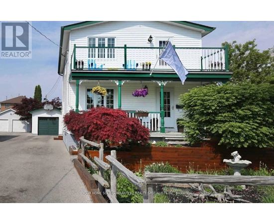 A white house with green trim and a balcony.