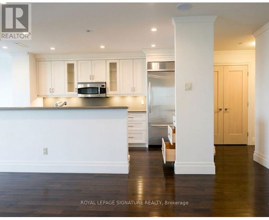 A kitchen with white cabinets and a stainless steel refrigerator.