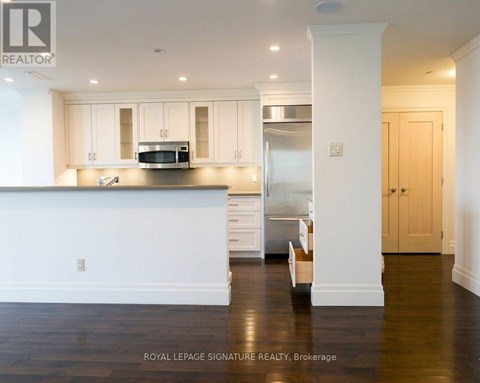 A kitchen with white cabinets and a stainless steel refrigerator.
