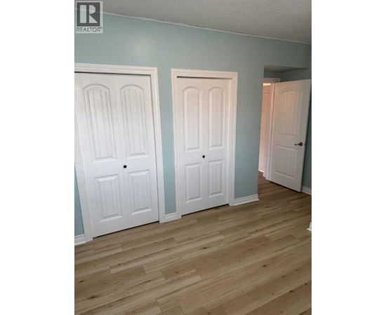 Three white doors in a room with wooden floors.