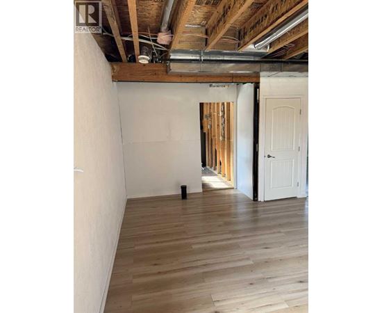 A room with wooden floors and walls, and a doorway leading to another room.