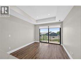 A spacious room with wooden floors and a sliding glass door leading to a backyard.