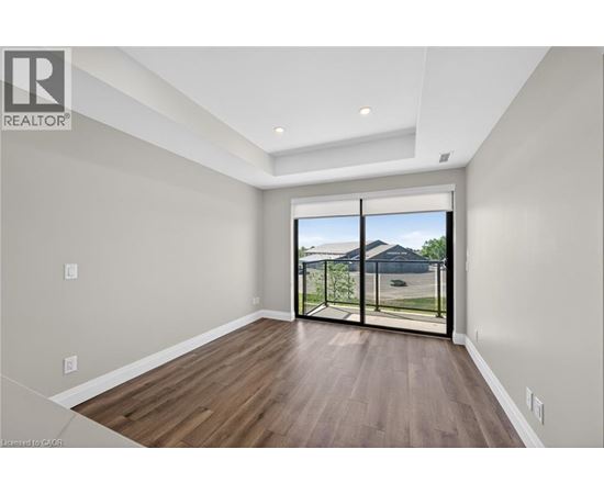 A spacious room with wooden floors and a sliding glass door leading to a backyard.