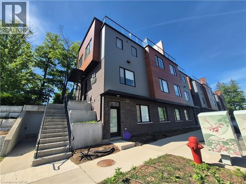 A red fire hydrant is in front of a building with a staircase.