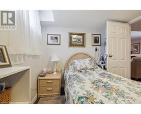 A bedroom with a floral bedspread and a white bedside table with a lamp on it.